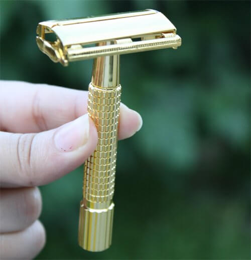 A man Shape his beard by gold razor.